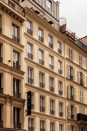 Un edificio de varios pisos con balcones, ventanas grandes y un letrero que indica un hotel.