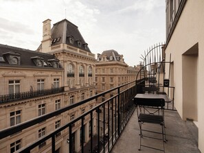 Ein Balkon mit Metallgeländer mit Blick auf eine Stadtlandschaft und historische Gebäude.