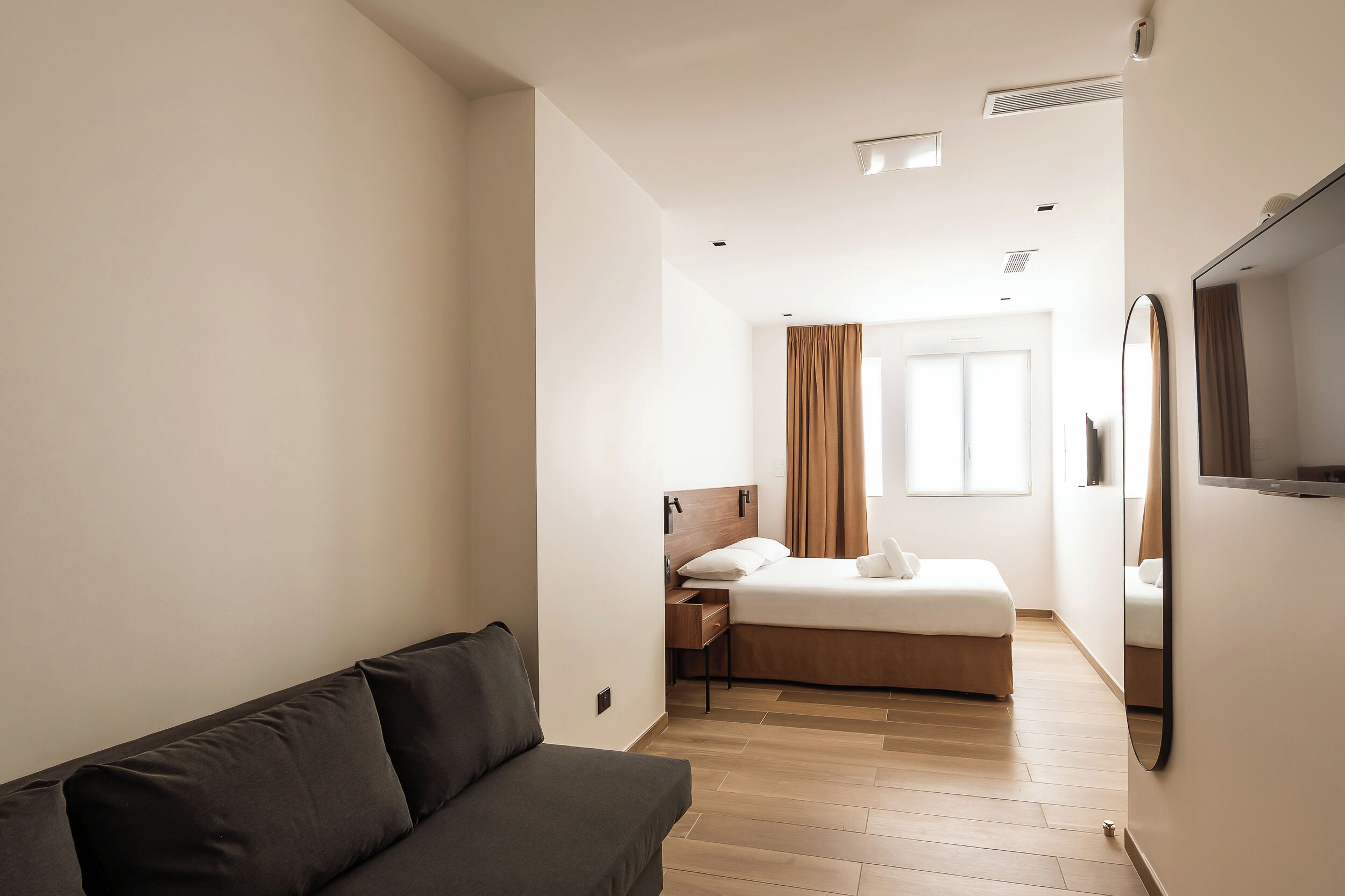 Una habitación de hotel moderna con sofá, cama, escritorio y televisión.