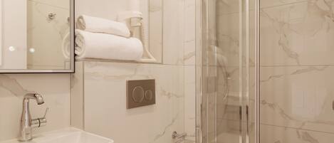 Un baño moderno con cabina de ducha de vidrio, inodoro blanco y pared revestida de mármol.