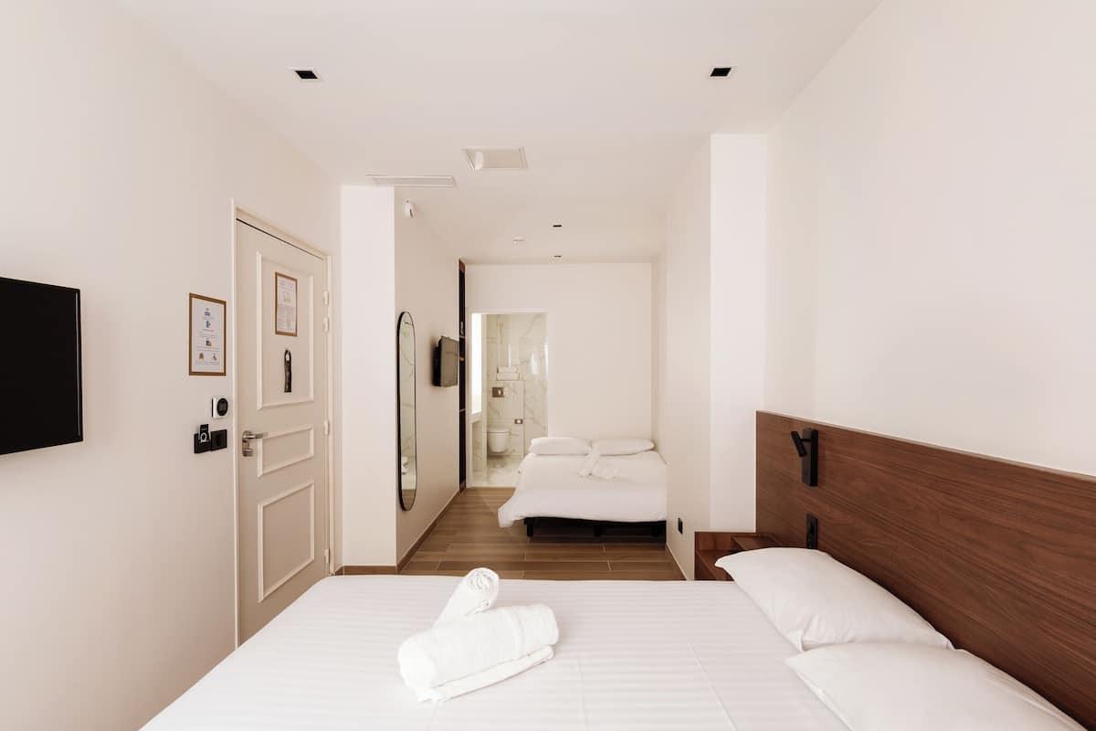 Ein Hotelzimmer mit Bett, Fernseher, Tür und einem Badezimmer im Hintergrund.