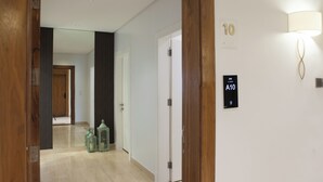 A hallway with a wooden door, a wall-mounted light, and a sign indicating room A10. - Darent Royal Threebedroom Al Malqa (Riyadh)