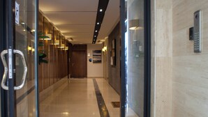A hotel corridor with a glass door entrance, a handrail, a wall-mounted phone, and a door with a sign. - Darent Royal Threebedroom Al Malqa (Riyadh)
