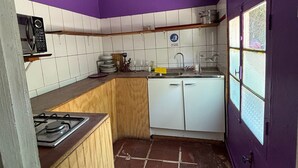 A compact kitchen with a gas stove, white cabinets, a sink, and a window with a view. - Oceana Suites San San José de Maipo II (San Alfonso)