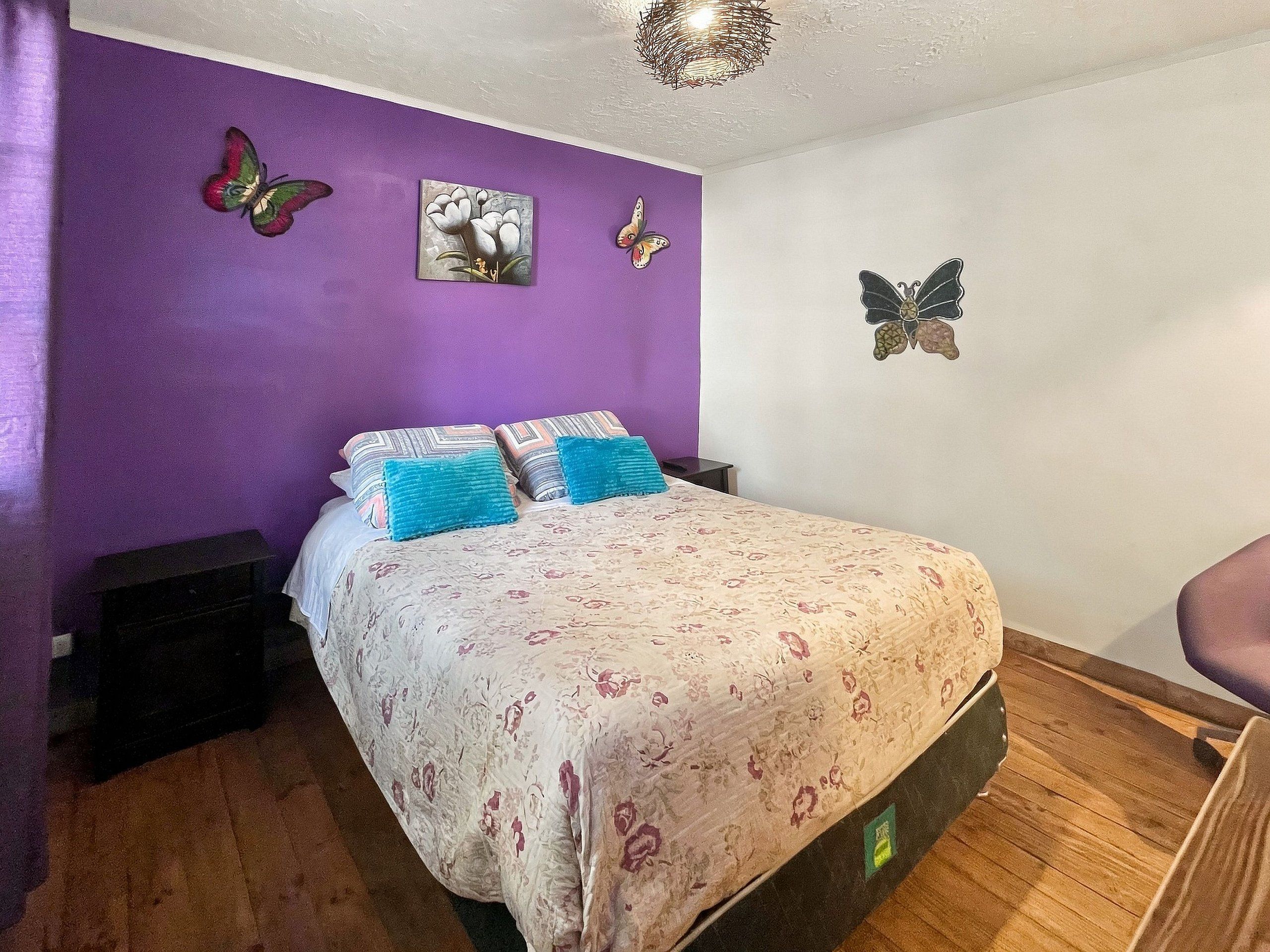 Un dormitorio con cama, almohadas, una obra de arte en la pared y una lámpara en el techo.