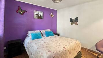 Un dormitorio con cama, almohadas, una obra de arte en la pared y una lámpara en el techo.
