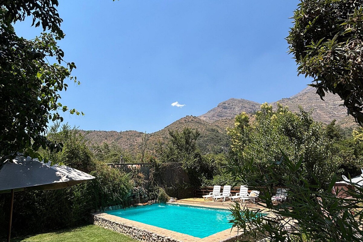 A swimming pool surrounded by a stone wall, with a view of mountains in the background.