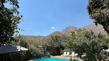 A swimming pool surrounded by a stone wall, with a view of mountains in the background.