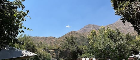 Una piscina rodeada por un muro de piedra, con vistas a montañas al fondo.