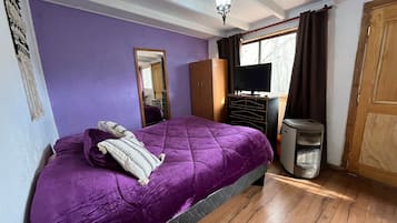 A bedroom with a bed, a dresser, a television, and a heater.