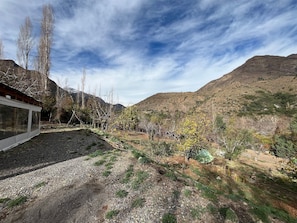 Un paisaje montañoso con un edificio de grandes ventanales, rodeado de árboles y un camino de grava.
