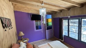 A room with a bed, a television, a chandelier, and a window with a view. - Oceana Suites San San José de Maipo II (San Alfonso)