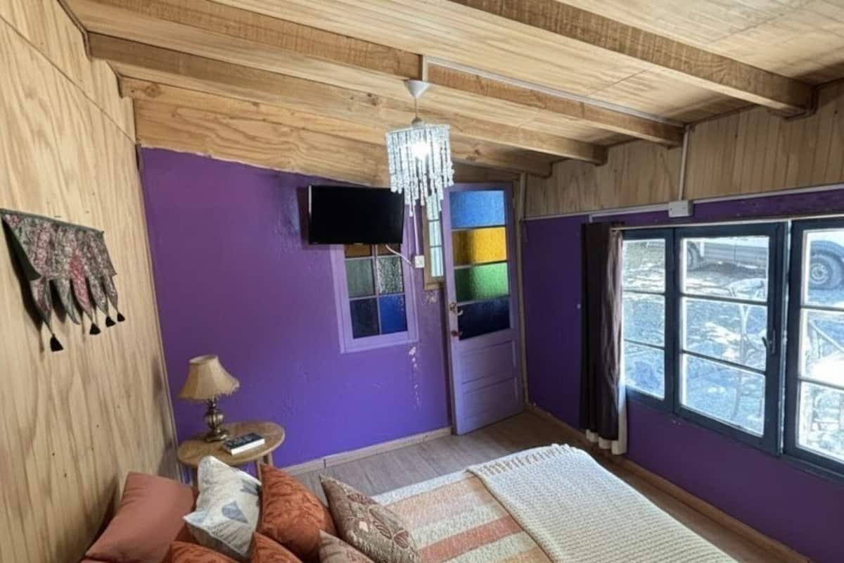 Ein Zimmer mit einem Bett, einem Fernseher, einer Chandelüster und einem Fenster mit Blick.
