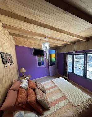 Una habitación con cama, televisión, candelabro y ventana con vistas.
