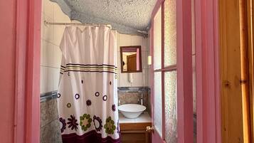 Un baño pequeño con inodoro, lavamanos y ducha.