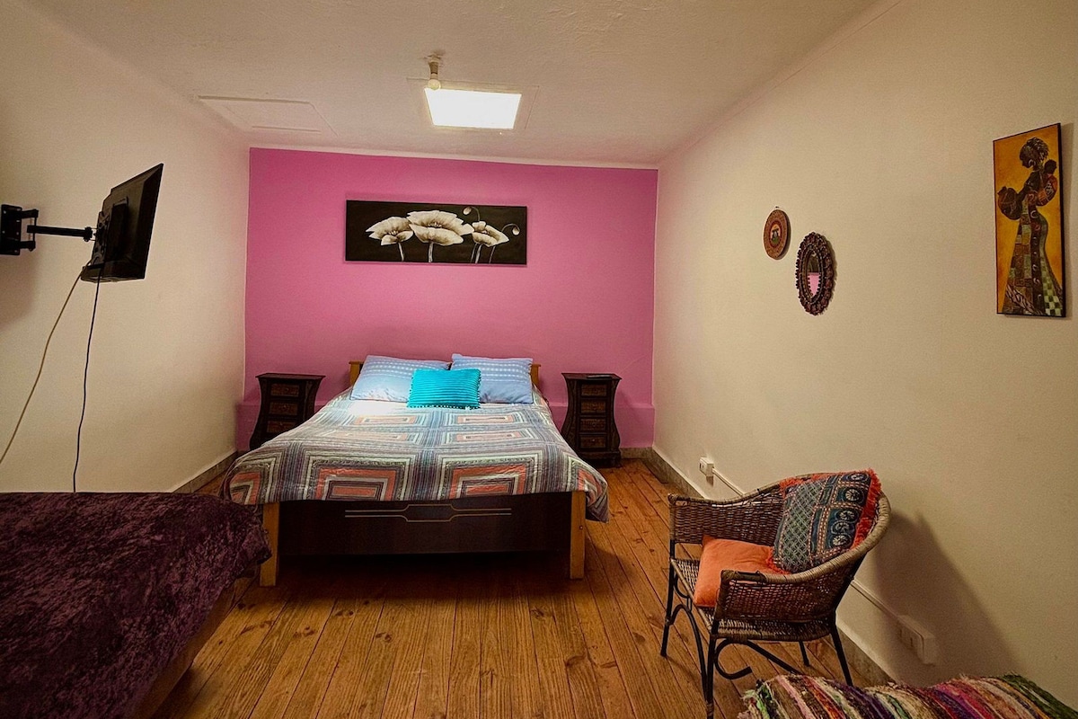 A room with a bed, a chair, a desk, and a ceiling light.