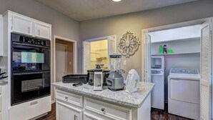 A kitchen with a built-in oven, a blender, a toaster, and a refrigerator.