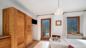 A room with wooden furniture, a dining table, and a view of trees through a window.