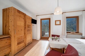 Ein Zimmer mit Holzmöbeln, einem Esstisch und Blick auf Bäume durch ein Fenster.