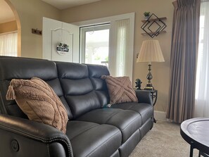 A black leather sofa with two throw pillows, a lamp, and a small table with a plant. - Fully Furnished Corporate Rental - 2 Kitchens + Private Suite - 30+ Day Stays (Barberton)