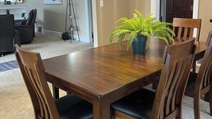 A dining area with a wooden table, chairs, a potted plant, and a chandelier. - Fully Furnished Corporate Rental - 2 Kitchens + Private Suite - 30+ Day Stays (Barberton)