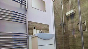 A bathroom with a glass shower enclosure, a white sink with a soap dispenser, and a towel rack. - Contemporary City Studio 4 - Contractor's & Traveller's Accommodation (Peterborough)