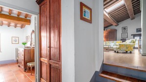 Un escalier menant à un espace de vie, avec une porte en bois, un radiateur et une chaise.