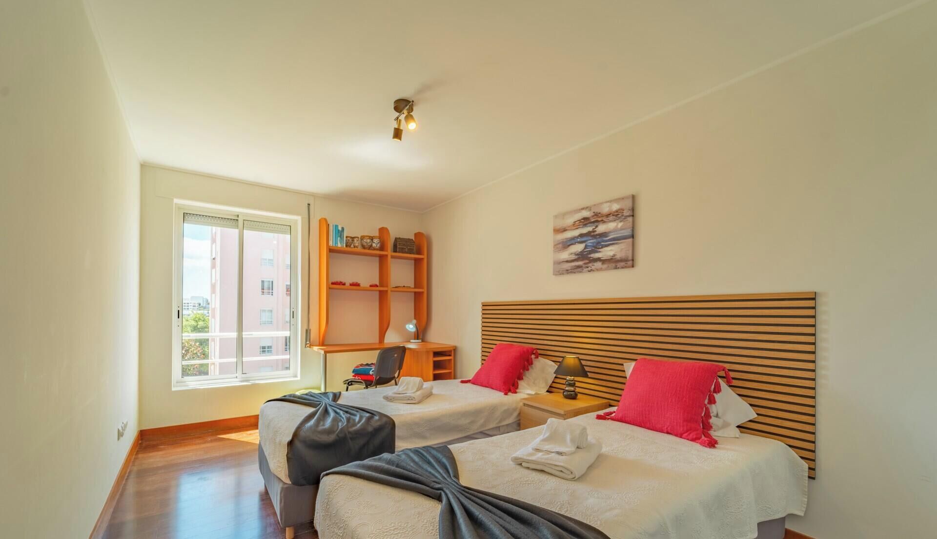 Un dormitorio con dos camas, un escritorio, una estantería y un cuadro en la pared.