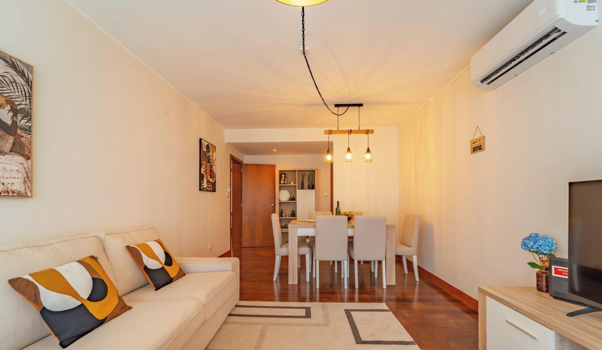 A modern living room with a sofa, dining area, and TV.