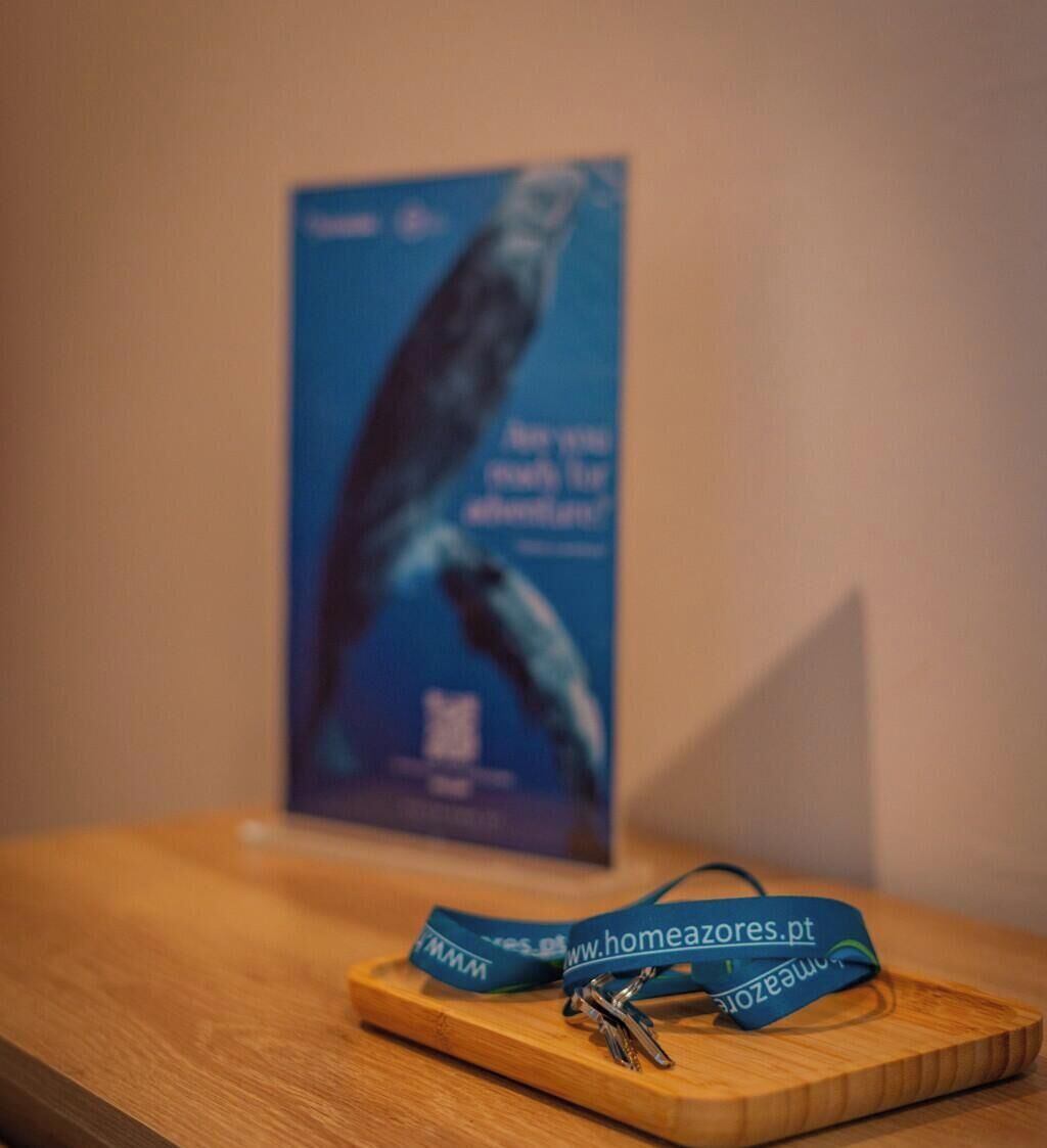 A wooden table with a blue lanyard and keys, and a poster in the background.