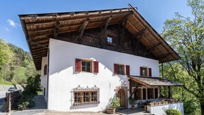 Un chalet traditionnel doté d’un toit à pente, de poutres en bois et d’une façade blanche.