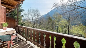 Une terrasse en bois avec une table et des chaises, offrant une vue sur un paysage montagneux.