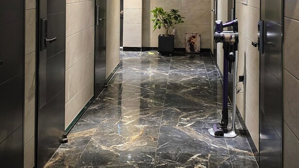 A hallway with dark tiled walls, a marble floor, and a plant in the center. - U Stay Hostel Gasan (Seoul)