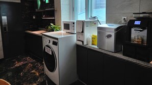 A modern kitchen with a washing machine, a coffee machine, and a microwave. - U Stay Hostel Gasan (Seoul)