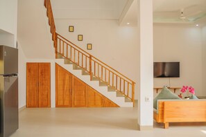 A modern interior with a wooden staircase, a flat-screen TV, and a bed with pillows. - Dolphin 4 – Deluxe Twin Room in New Villa on Lovina Beach (Buleleng)
