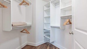A walk-in closet with open shelves, hanging space, and a metal rack. - Modern Apt Heart of Seaport (Boston, MA)