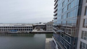 A modern building with a dock extending into a calm body of water, surrounded by other structures. - Modern Apt Heart of Seaport (Boston, MA)