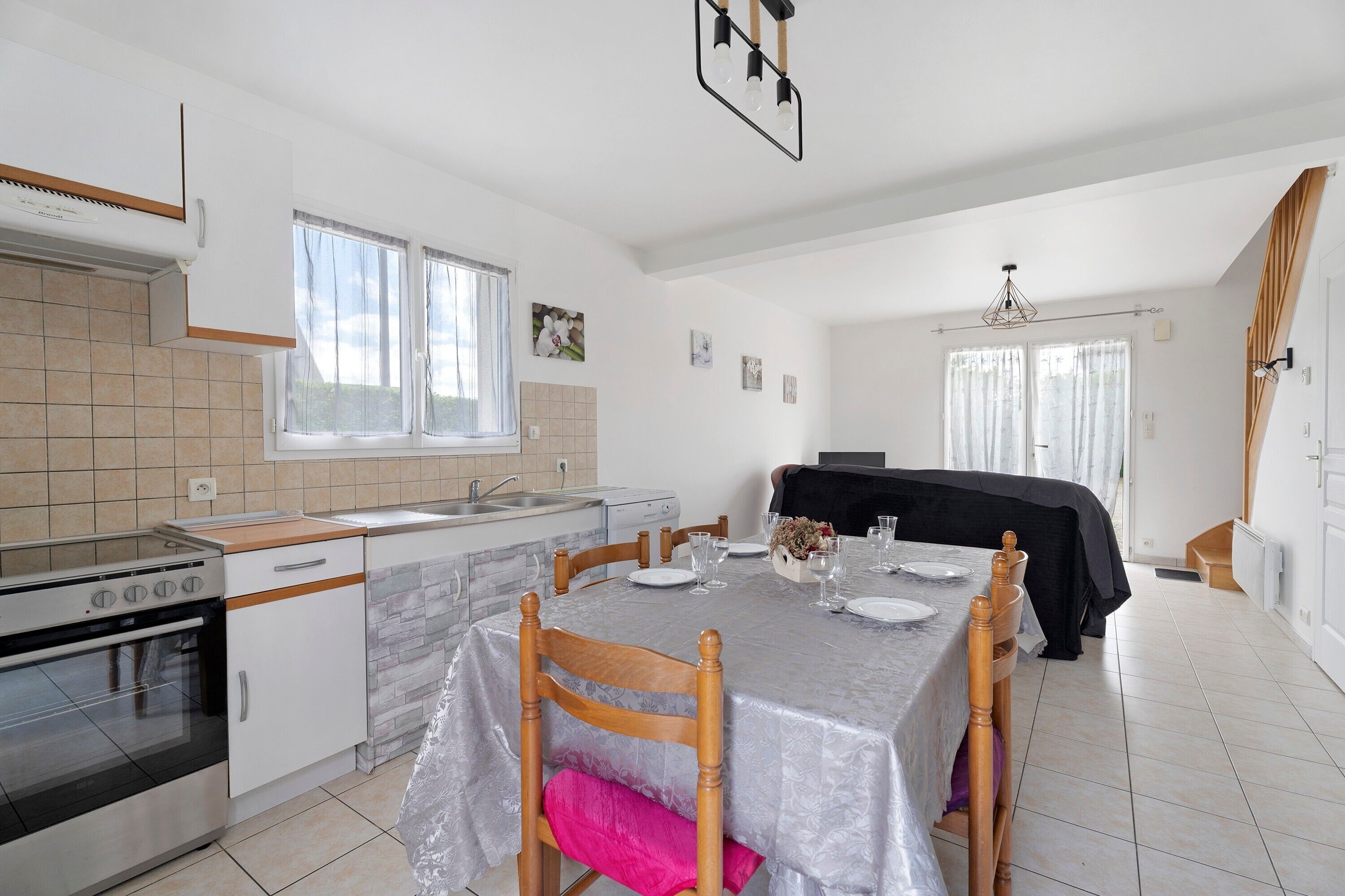 Une cuisine équipée d’une cuisinière, d’un évier et d’un coin repas avec des chaises et une table mise pour deux personnes.