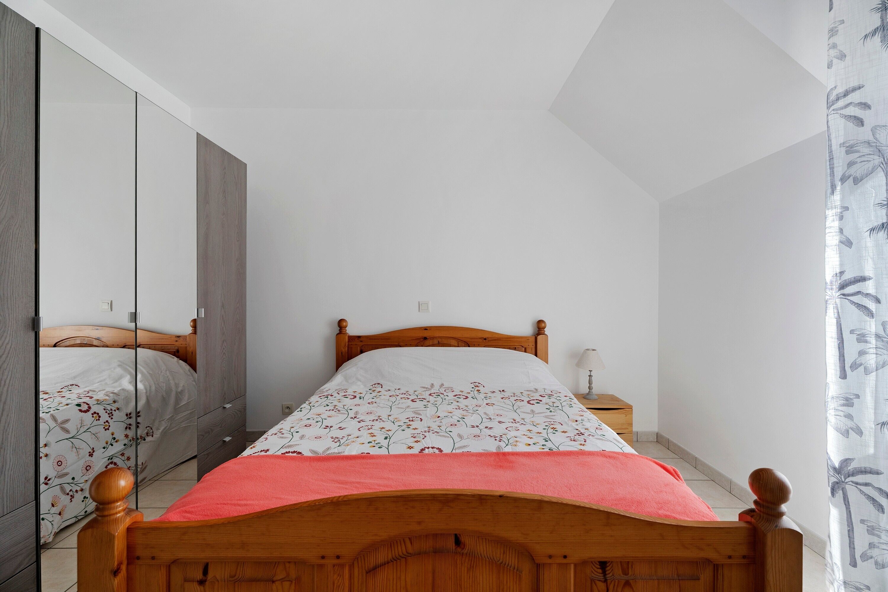 Un dormitorio con una cama de madera, una mesita de noche, un espejo y un armario.