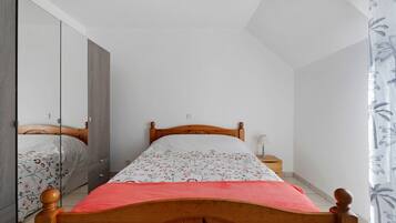 Un dormitorio con una cama de madera, una mesita de noche, un espejo y un armario.