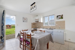 Una cocina con una mesa de comedor para cuatro personas, lavavajillas y una ventana con vistas al exterior.