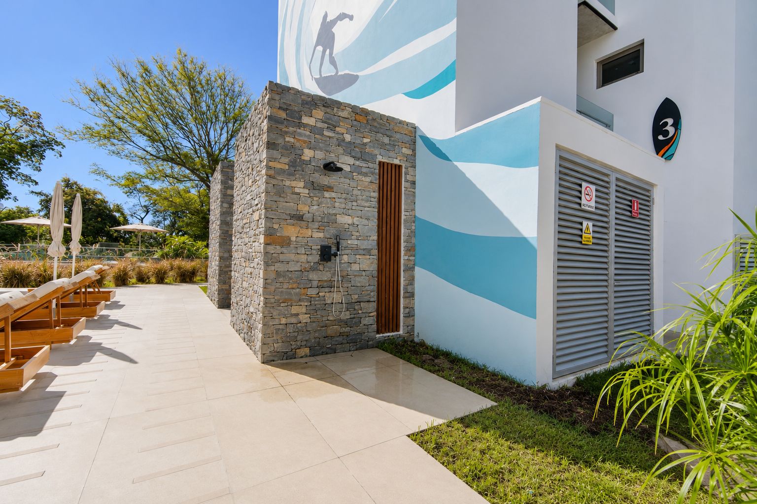 Un bâtiment doté d’une façade en pierre, d’une fresque représentant une vague bleue et d’un panneau indiquant le chiffre « 3 ».
