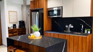 Een moderne keuken met een centraal eiland, houten kastjes, een ingebouwde magnetron en een achterwand van zwart marmer.