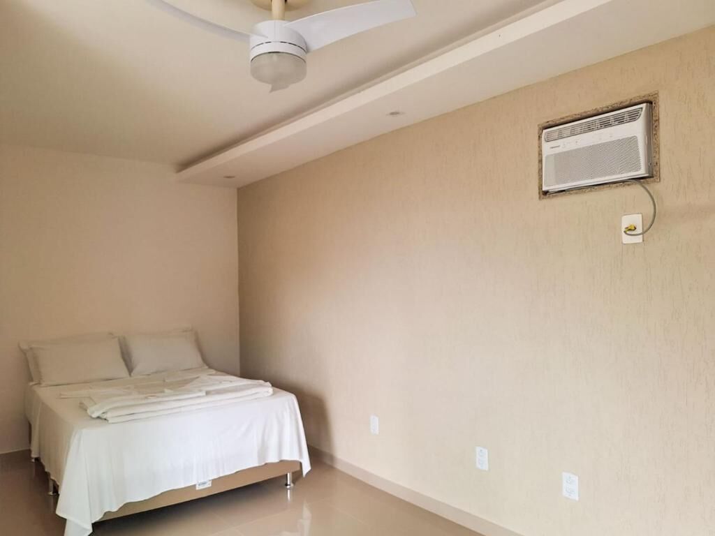 A bedroom with a bed, a ceiling fan, and an air conditioning unit.