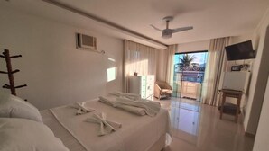 Une chambre d’hôtel avec un lit, un ventilateur de plafond, une télévision et une vue sur l’extérieur.