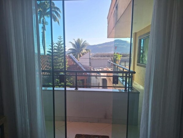 A balcony with a view of palm trees and buildings. - Sintonia com Mar (Angra dos Reis)