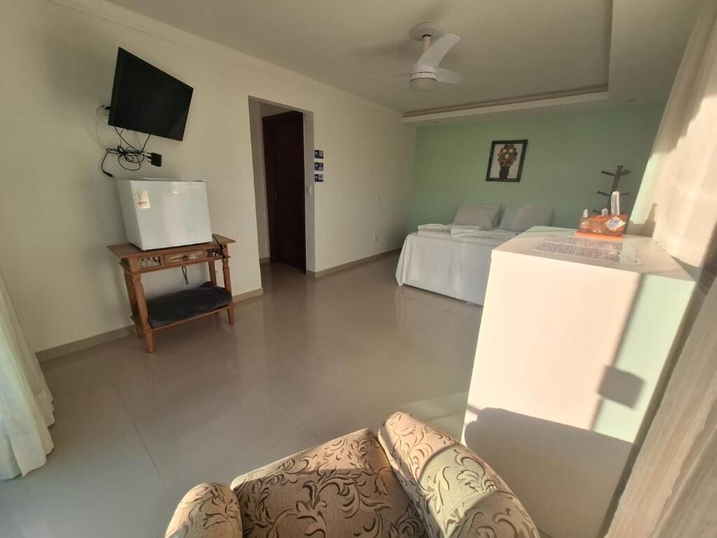 Una sala de estar con televisión, refrigerador, sofá y cama.