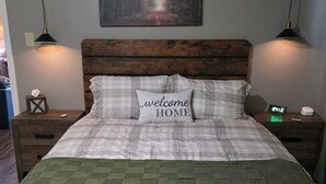A bedroom with a bed, a bench, a nightstand, a wall clock, and a painting. - Cozy Country Cottage in enchanting Statesboro with AC (Statesboro)