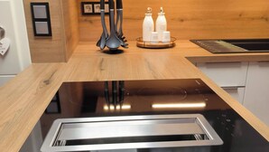 Una cocina con estufa negra, encimera de madera y pileta de acero inoxidable.