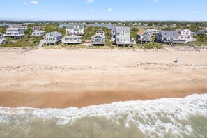 A beachfront property with multiple houses, a sandy beach, and a view of the ocean. - Direct Oceanfront on Charleston Beach! (Charleston)